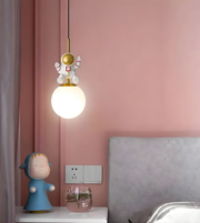 Pendant light with decorative character against a pink wall
