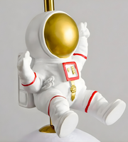 White astronaut figurine with a gold helmet on a gray background
