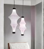 Two pendant lights hanging from the ceiling in a room with a bed in the foreground.