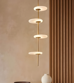 Modern pendant light fixture against a beige wall with a brown curtain.