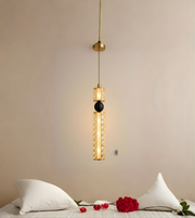 Modern pendant light fixture hanging above a bed with white pillows and red roses.