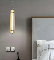 Modern pendant light fixture hanging above a bed in a bedroom setting.