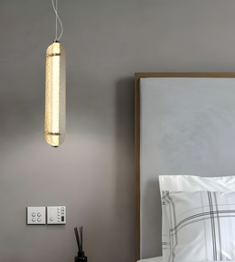 Modern pendant light fixture hanging above a bed in a bedroom setting.