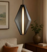 Modern pendant light hanging in a living room with a couch and decorative items.