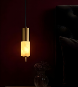 Gold pendant light fixture in a dark room with a vase of flowers on a table.
