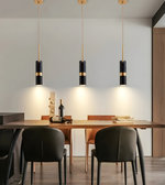 Dining room with wooden table, black chairs, and pendant lights.