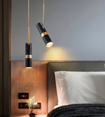 Modern bedroom with black and gold pendant lights, bed, and decorative elements.