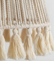 Close-up of a macrame wall hanging with tassels on a white background