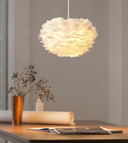 Fluffy white pendant light hanging above a wooden table with decorative items.