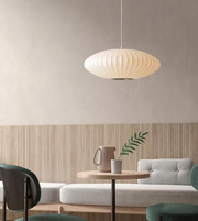 Modern interior with a pendant light, table, and sofa against a neutral wall.