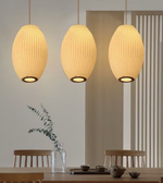 Three pendant lights hanging above a dining table with a minimalistic background.