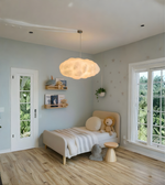 Children's bedroom with a bed, teddy bear, and cloud-shaped pendant light.