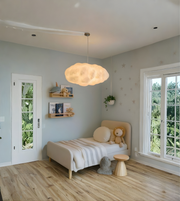 Children's bedroom with a bed, teddy bear, and cloud-shaped pendant light.