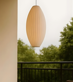 Wooden pendant light hanging outdoors with trees in the background