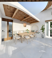 Modern outdoor dining area with wooden table and chairs, white walls, and wooden ceiling.
