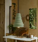 Green pendant light hanging above a table in a room with plants and decor.