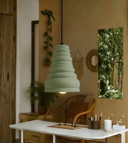 Green pendant light hanging above a table in a room with plants and decor.