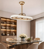 Luxury oval crystal fan chandelier with gold finish installed above a modern dining table