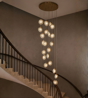 Modern gold multi-drop LED chandelier installed in a luxury double height living room staircase