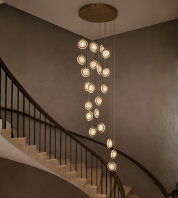 Modern gold multi-drop LED chandelier installed in a luxury double height living room staircase