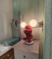 Pink cartoon mouse lamp glowing with soft ambient light on bedside table