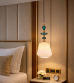 Elegant bedside hanging lamp with teal glass detailing and warm glow