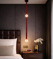 dual ring leather strap pendant light with warm glow hanging beside bed, modern luxury bedroom lighting
