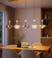 modern multi glass pendant lights in mixed finishes hanging above dining table, warm ambient lighting