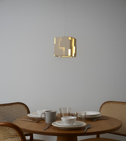 Modern off-white geometric cube pendant light hanging above dining table with soft ambient lighting