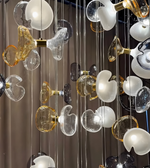 Modern chandelier with glass shades in various colors hanging against a dark background