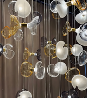 Modern chandelier with glass shades in various colors hanging against a dark background