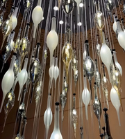 Decorative chandelier with hanging glass bulbs against a brown wall.