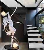 Modern interior with a decorative sculpture of a dancer and a staircase.