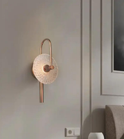 Modern wall sconce with decorative design on a neutral wall.