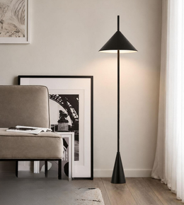 Modern black floor lamp in a room with a sofa and framed picture on the wall.