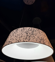 Pendant light with textured brown shade and white interior against a dark background