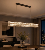Modern rectangular chandelier hanging above a dining table with decorative elements.