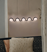 Modern pendant light fixture hanging in a room with patterned walls.