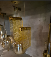 Gold textured pendant light fixture on a concrete wall background