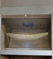Chandelier hanging from a ceiling in a room with wooden flooring.
