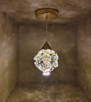 Crystal pendant light hanging from a ceiling in a room with textured walls.