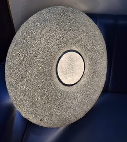 Round stone object with a central circular cutout on a dark blue background