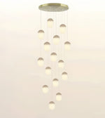 A modern multi-light pendant chandelier with a circular brushed gold ceiling canopy and multiple hanging frosted glass globes of varying sizes, shown against a plain light background.