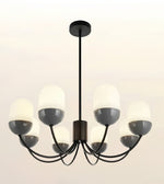 A modern 6-light chandelier with a matte black metal frame and semi-opaque white glass shades, shown against a plain off-white background.