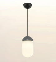 A modern pendant light fixture with a matte black ceiling canopy and cord, featuring a frosted white cylindrical glass shade with a dark gray metallic collar, shown against a plain off-white background.