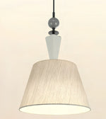 A modern pendant light fixture with a large tapered drum shade featuring vertical pleats, a white cone-shaped neck, a dark gray spherical accent, and a black hanging cord against a plain off-white background.