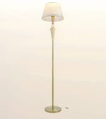 A mid-century modern floor lamp with a tapered white fabric shade, a fluted cream-colored stem, and a slim brass base on a light beige background.