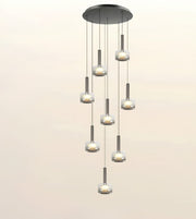 A modern multi-light linear chandelier with seven cascading glass shades and brushed metal accents, shown against a plain light beige background.