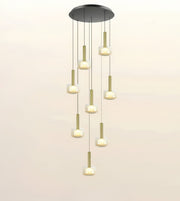 A modern multi-light linear pendant chandelier with a circular black ceiling canopy, gold-toned vertical rods, and frosted cylindrical glass shades that glow with warm light, shown against a plain off-white background.