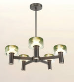A modern 5-light chandelier with a dark bronze metal frame and translucent green glass shades, shown illuminated against a plain off-white background.